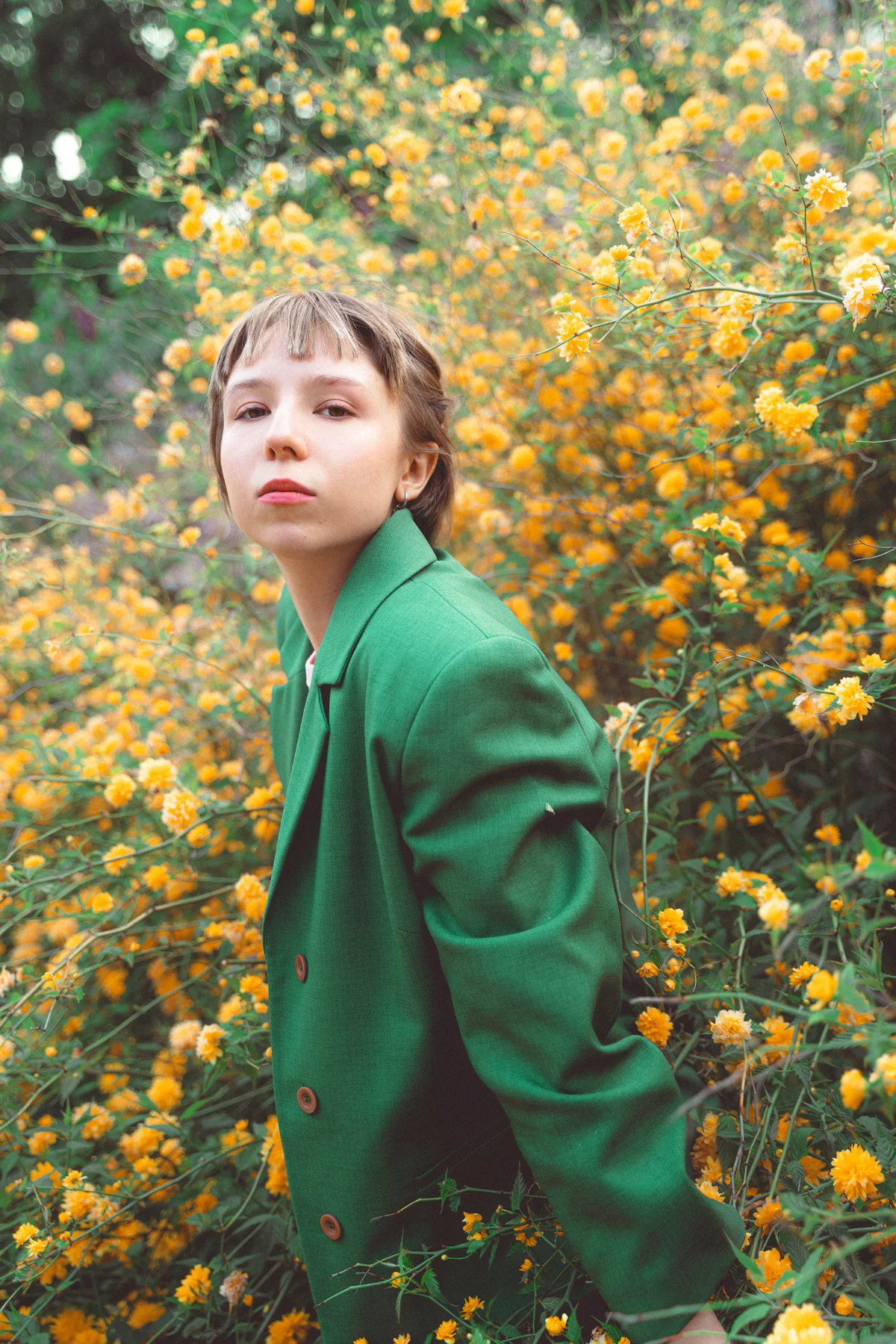 Girl in green jacket with yellow flowers behind her