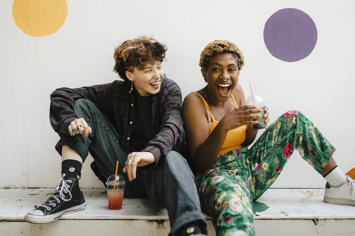 Two teens sitting and laughing with tea drinks