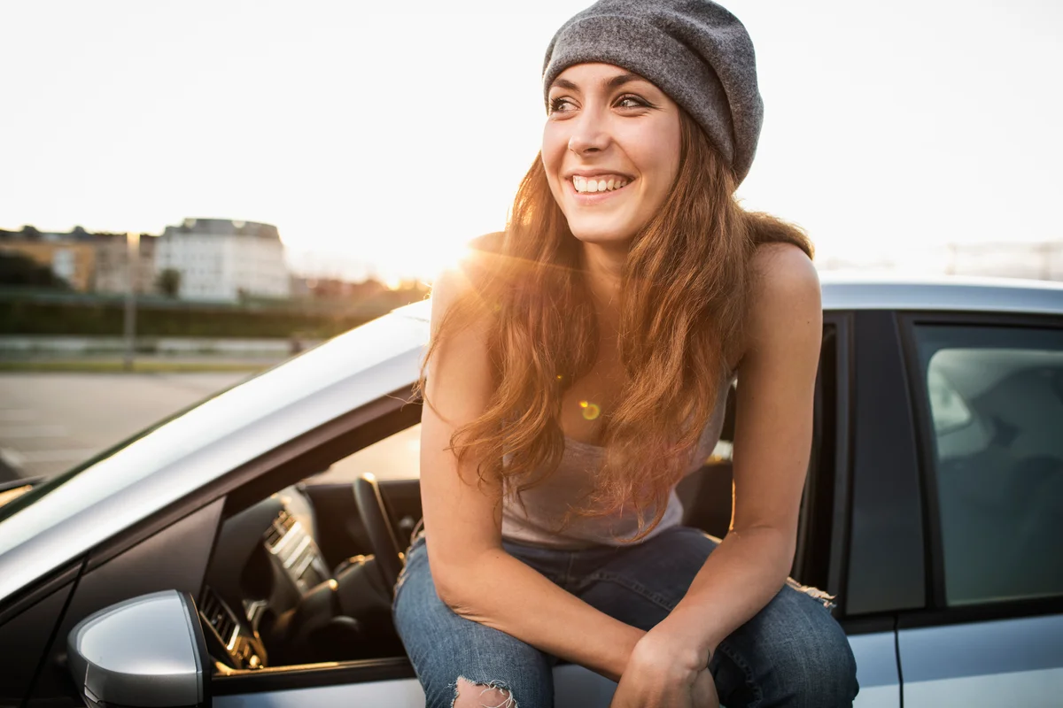 Confident woman sitting on car