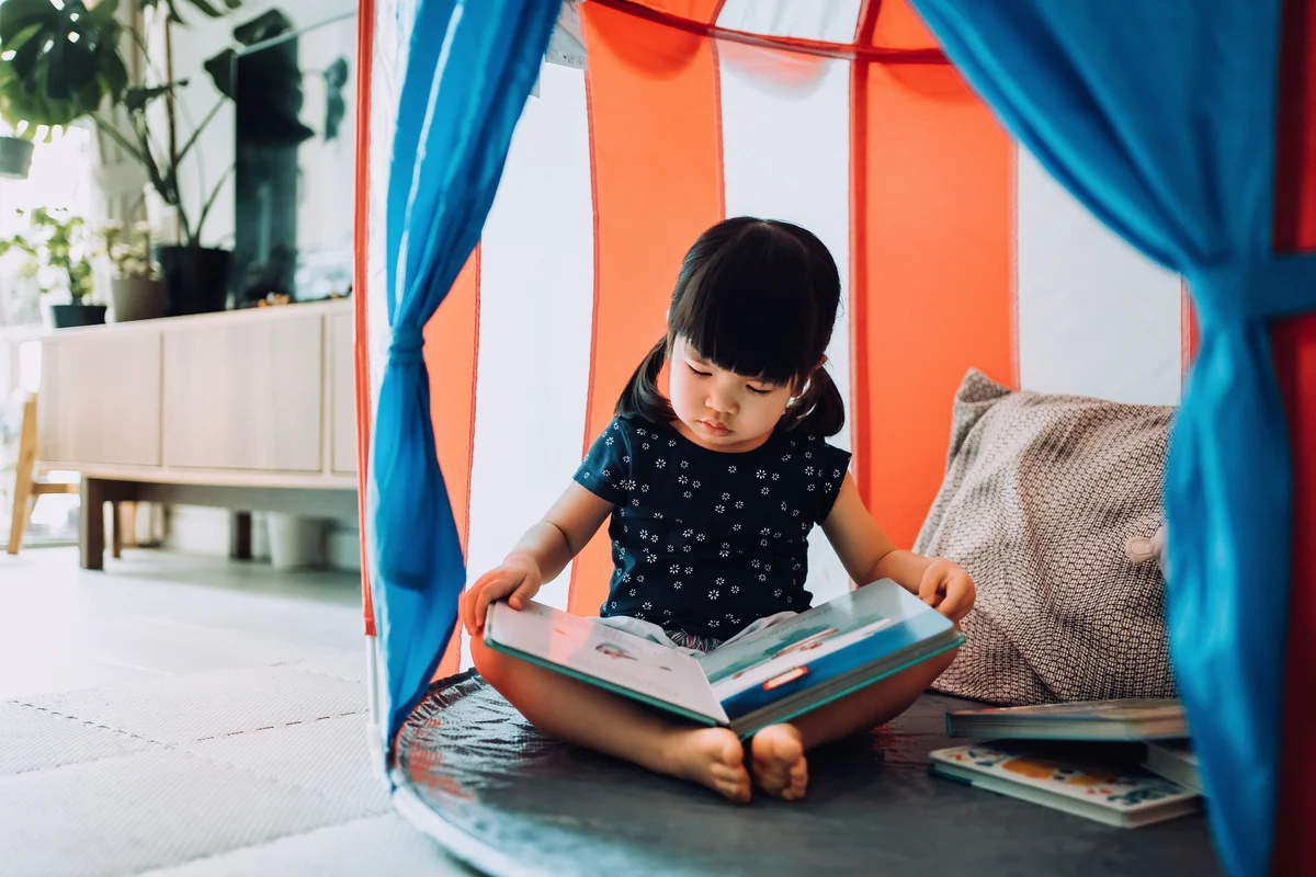 Little girl reading book in her room