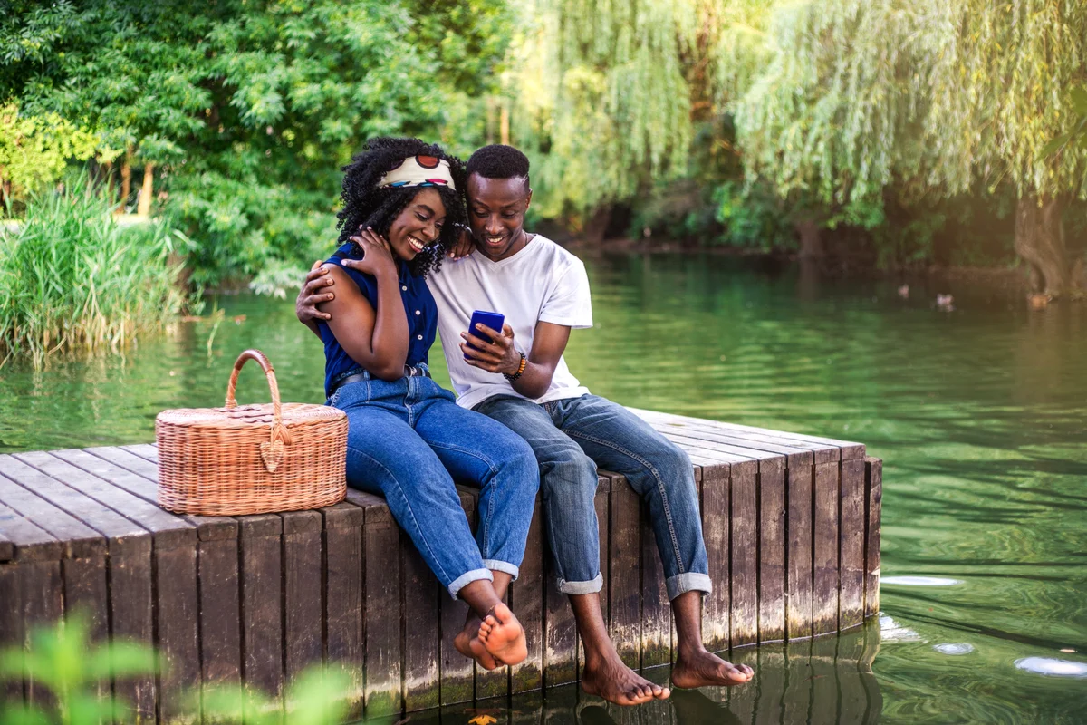young couple having picnic on a dock with feet in the water