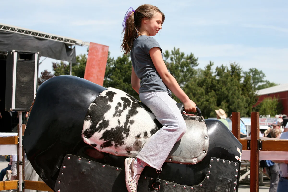 Girl Rides Mechanical Bull at Rodeo