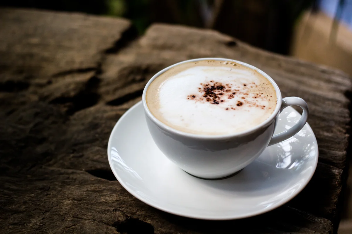 White mug with coffee and cinnamon sprinkled on top