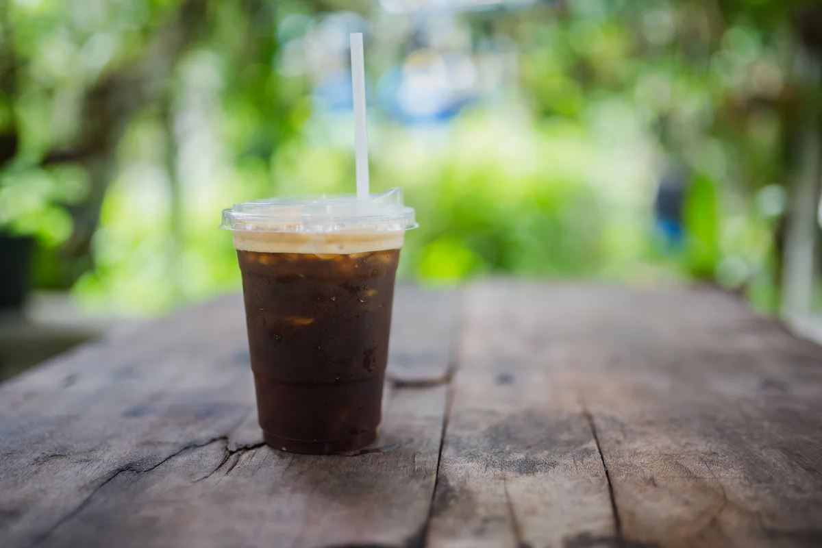 Iced americano in plastic cup on picnic table