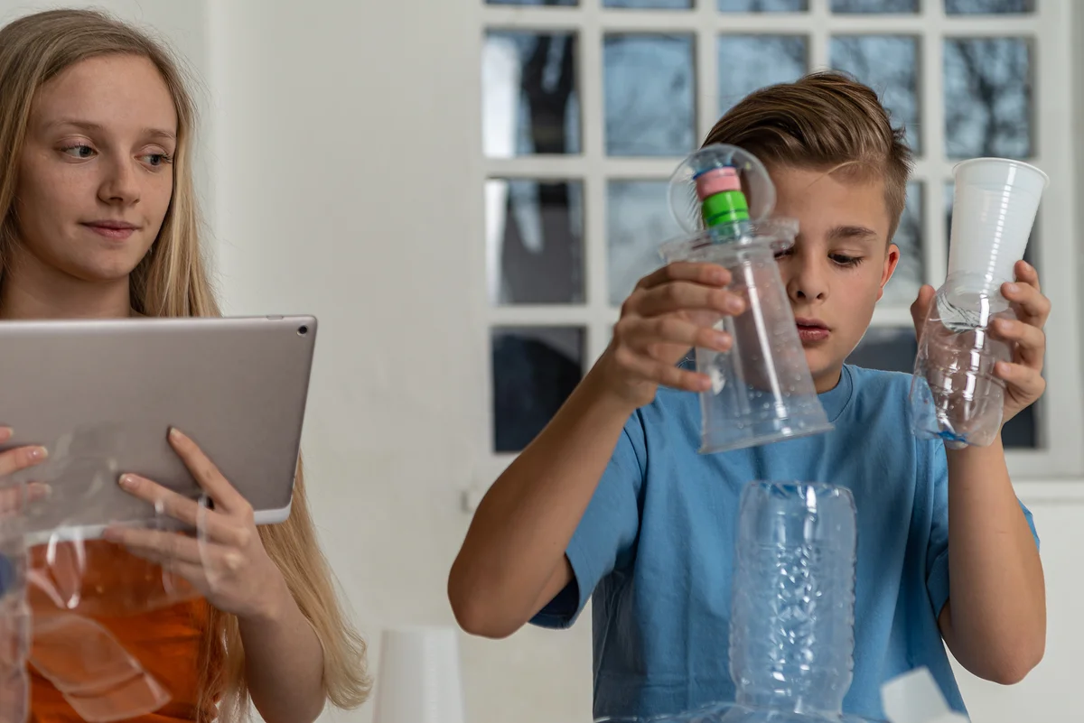 Boy and sister crafting with bottles and cups