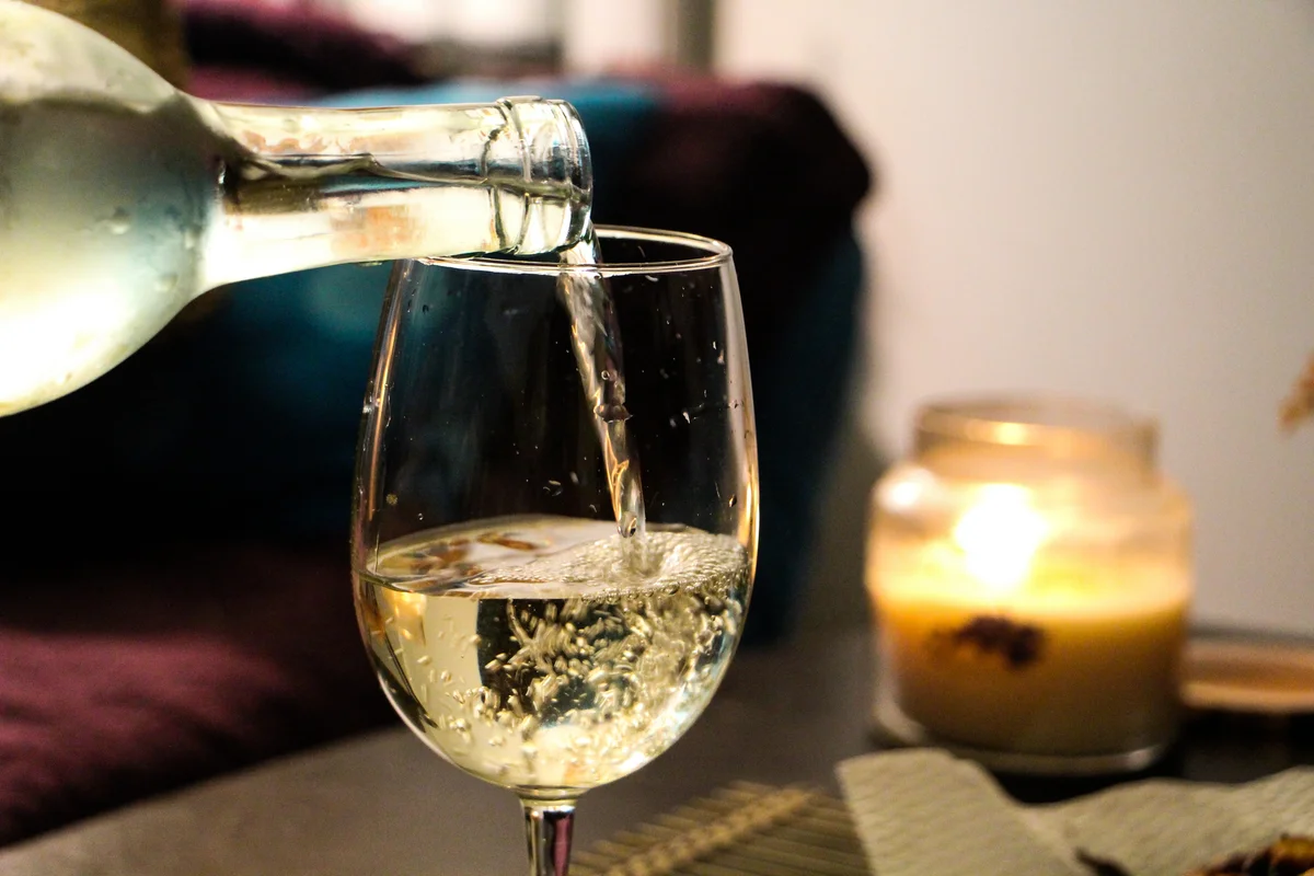pouring white wine by candlelight