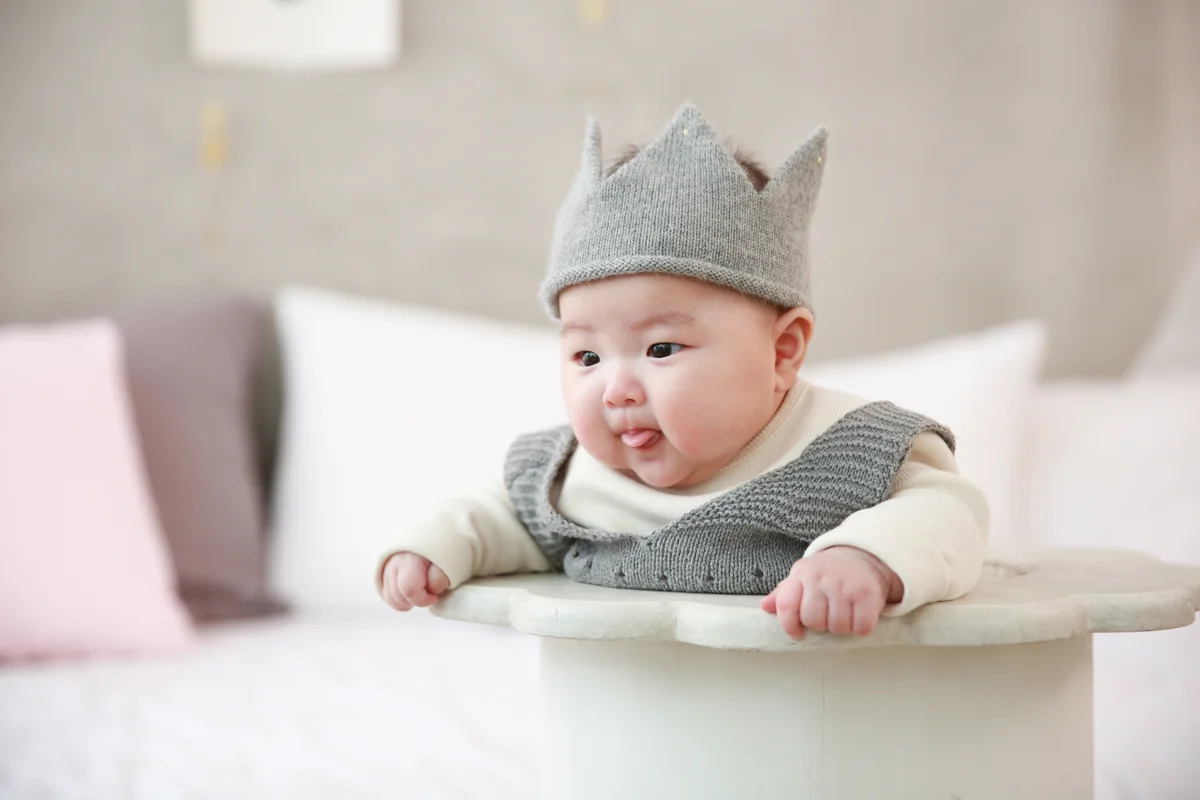 baby in a high chair wearing felt crown