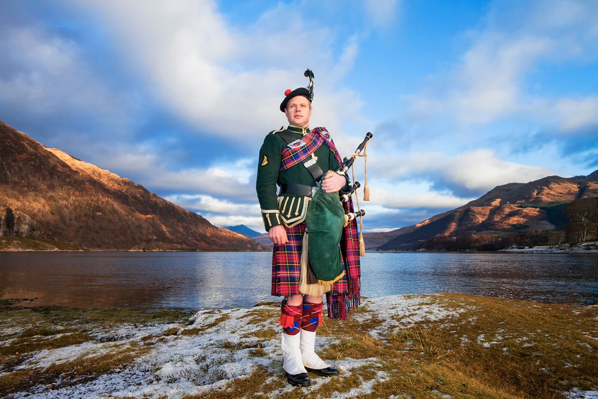 Bagpiper standing next to Loch Etive