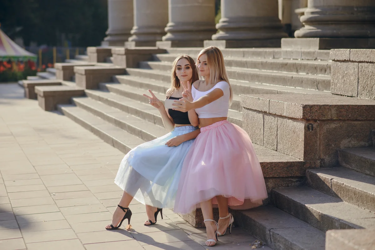 Girls in matching skirt outfits taking photos on stairs