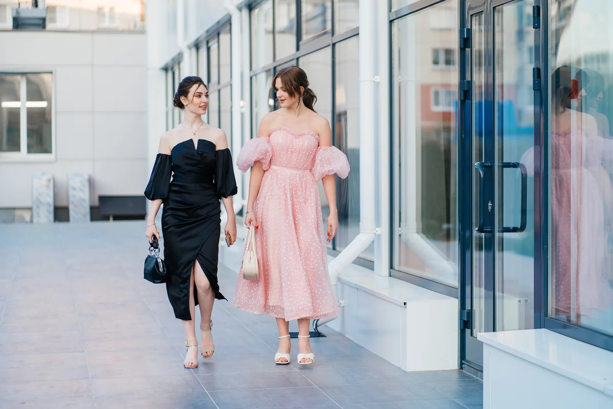 Two girlfriends in evening dresses go to a party