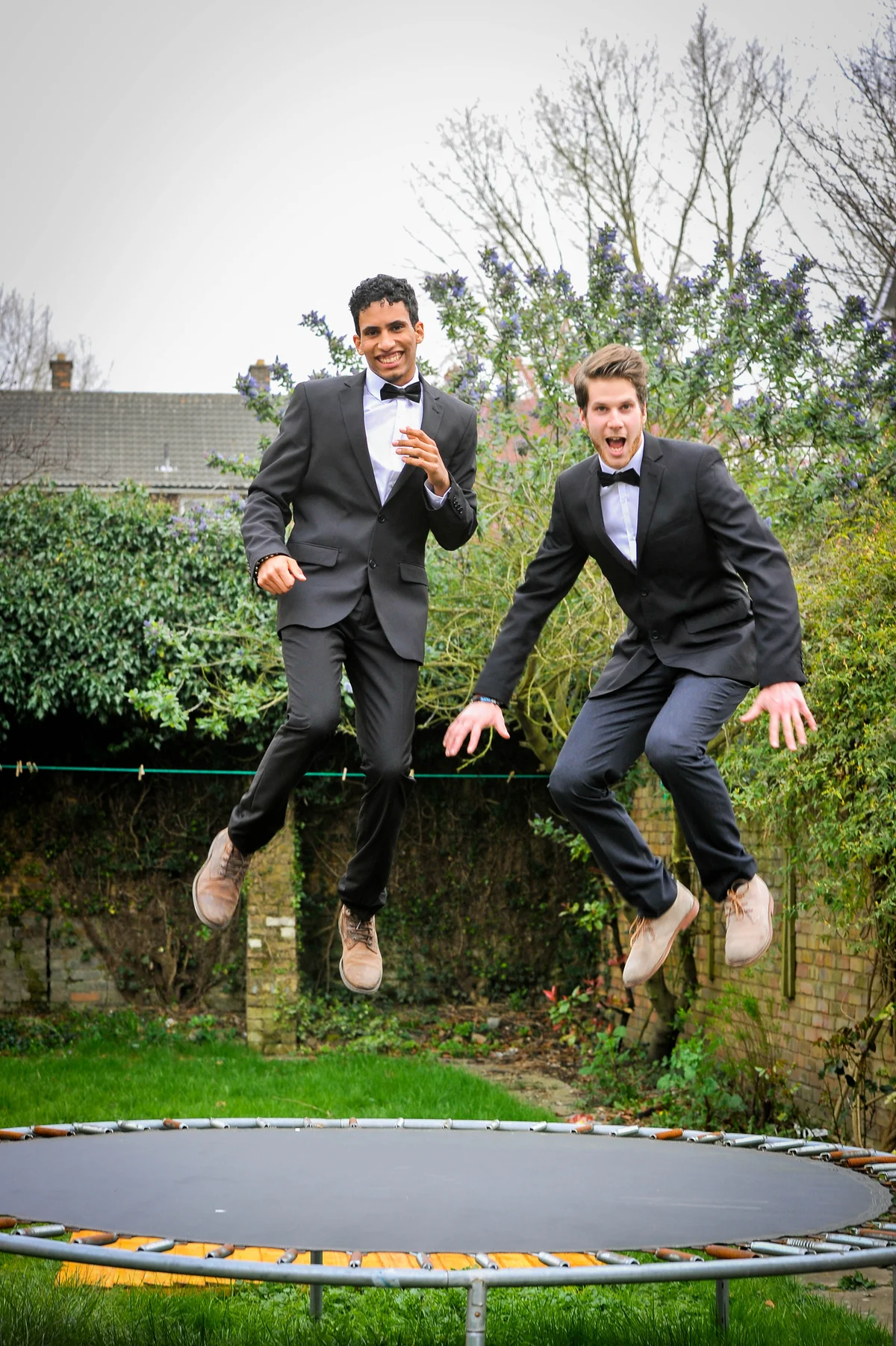 Two guys in formal suits jumping on trampoline