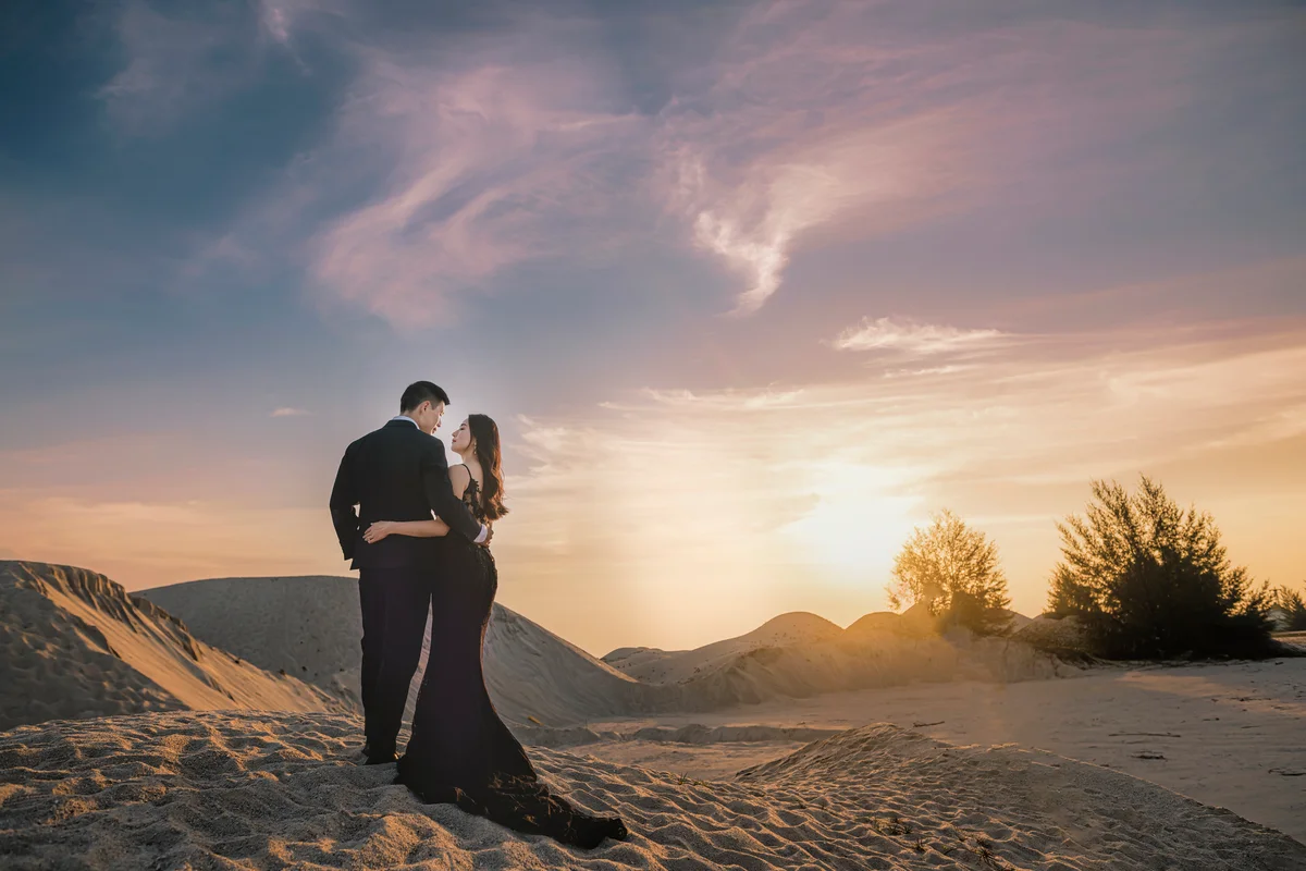 Couple in formalwear posing at scenic dunes