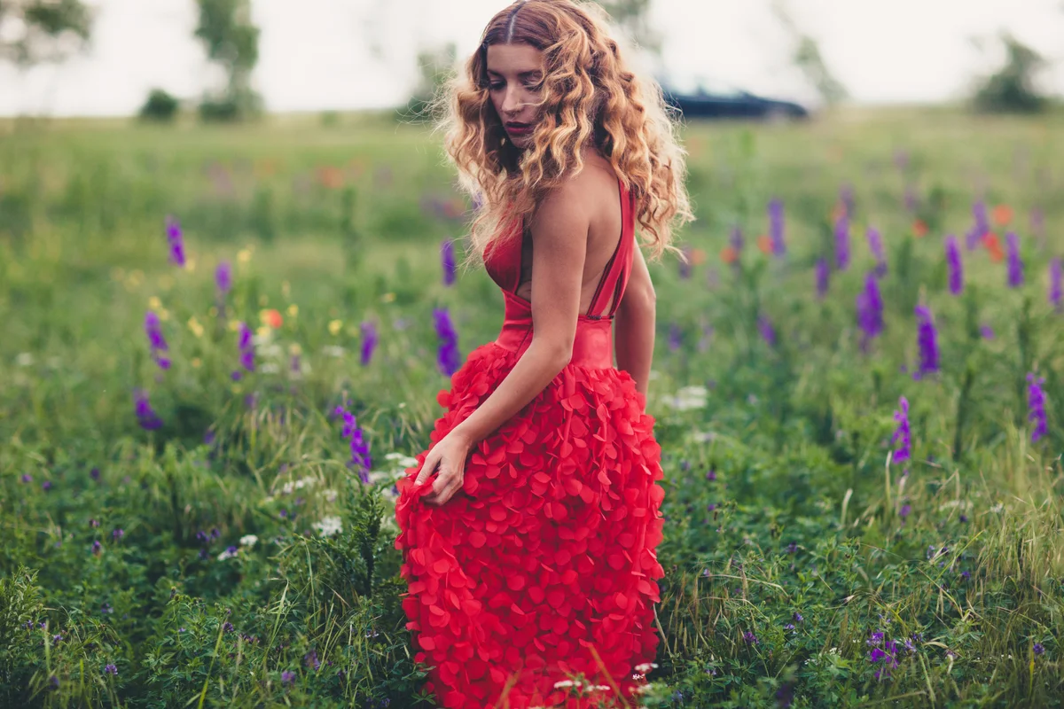 Girl in red dress posing in field of purple flowers