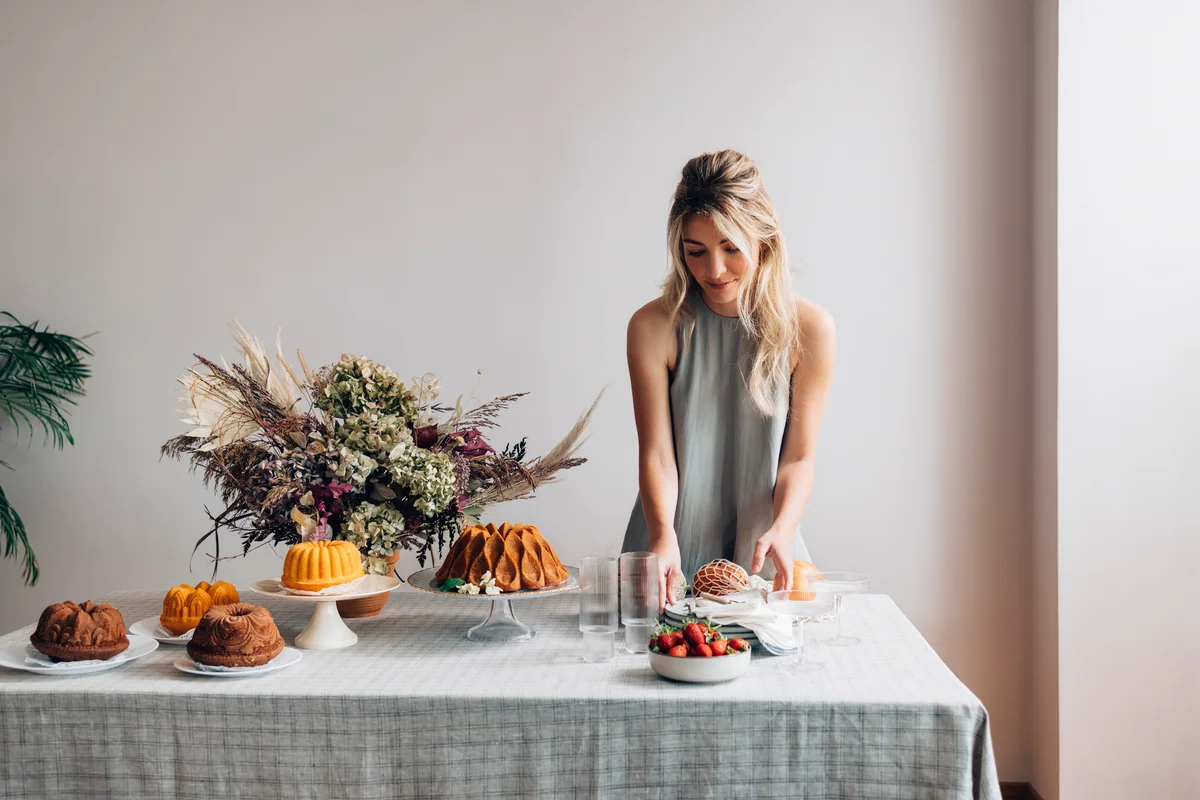 woman laying out bundt cakes on a dessert table