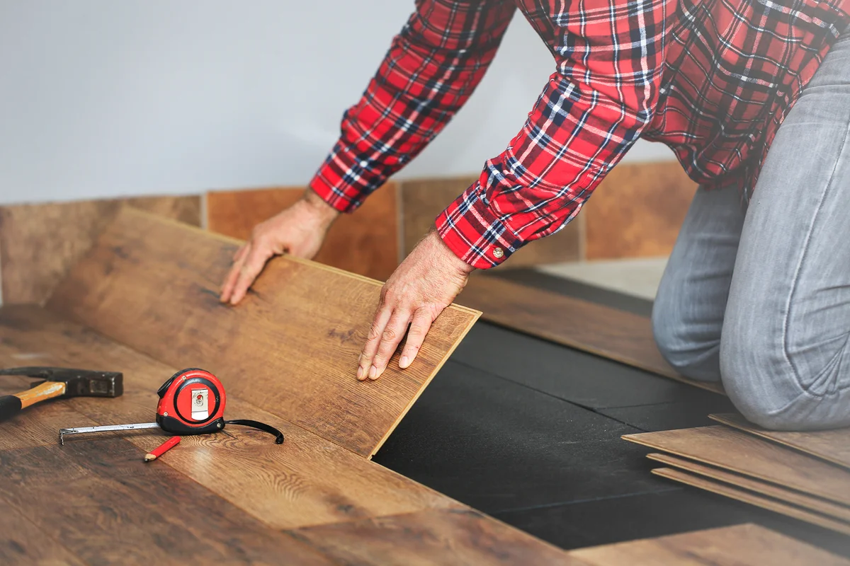 Worker hands installing timber laminate floor in the room