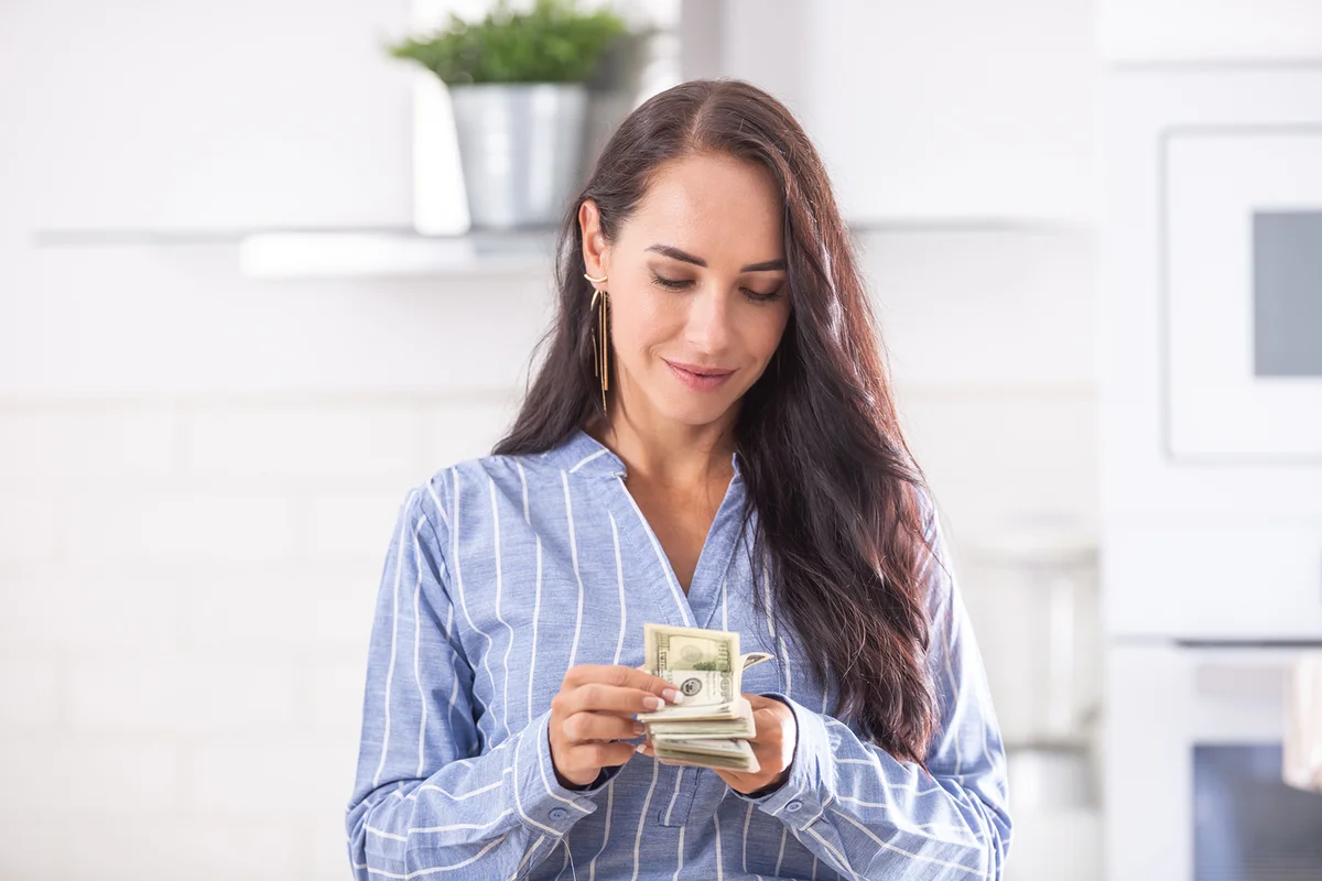 Young housewife recalculates the money she has saved for the household budget