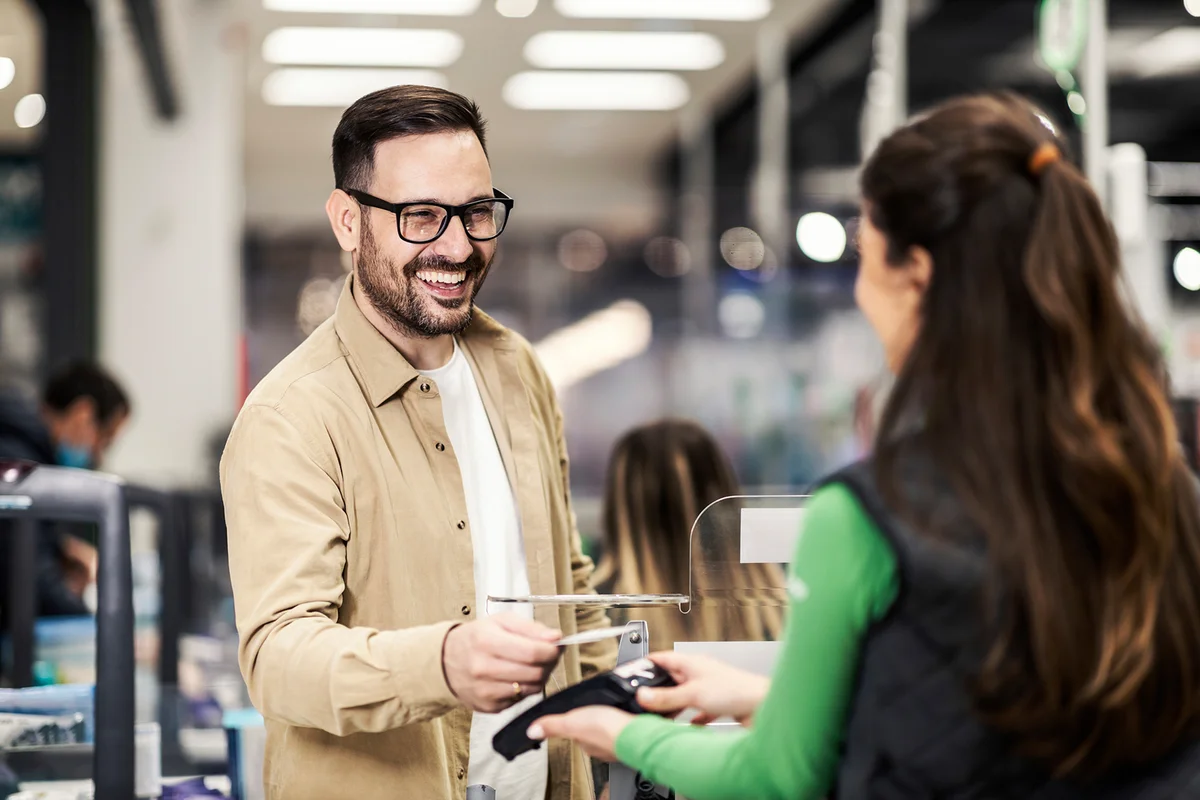 A happy customer paying at checkout with credit card in supermarket
