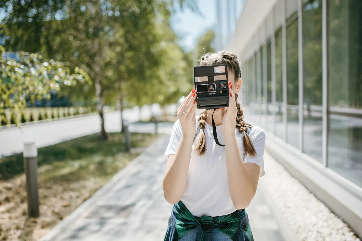 Young woman using a vintage polaroid camera