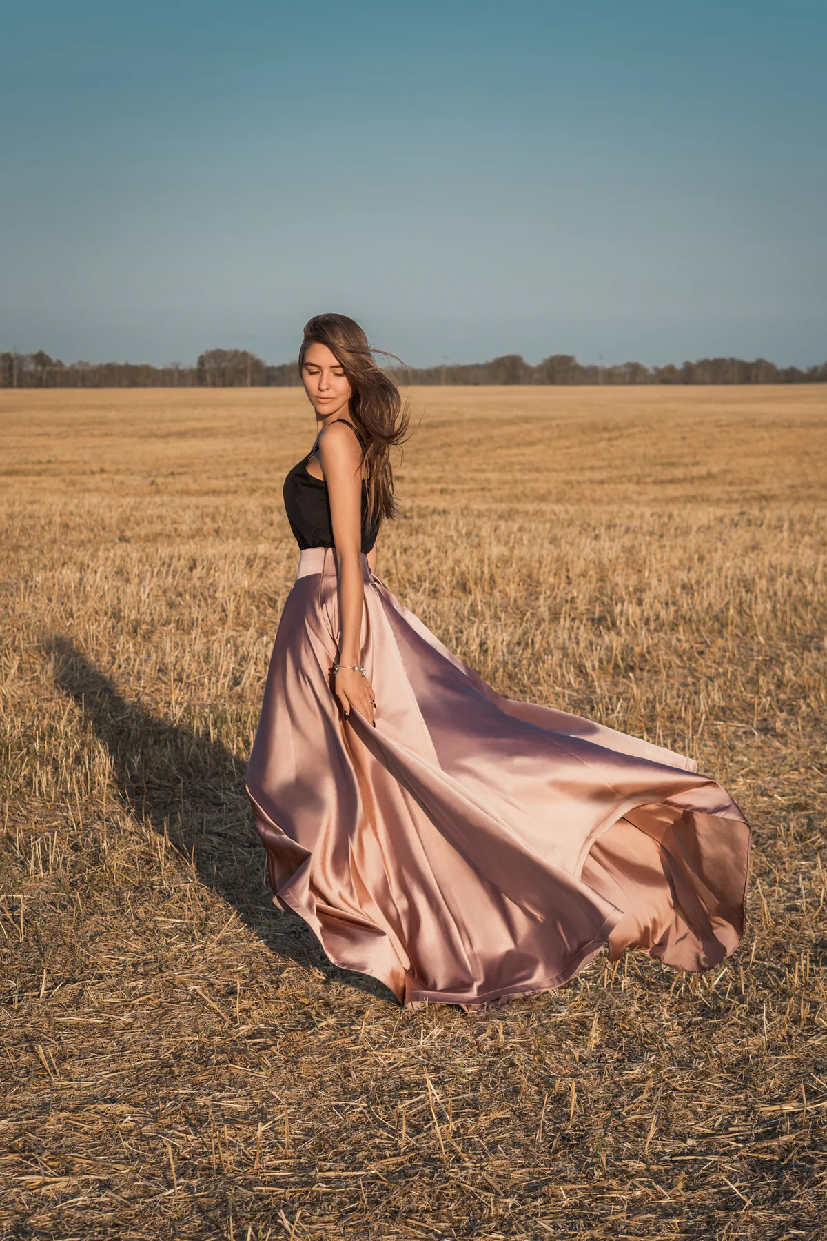 Girl posing solo in field with gown blowing in wind