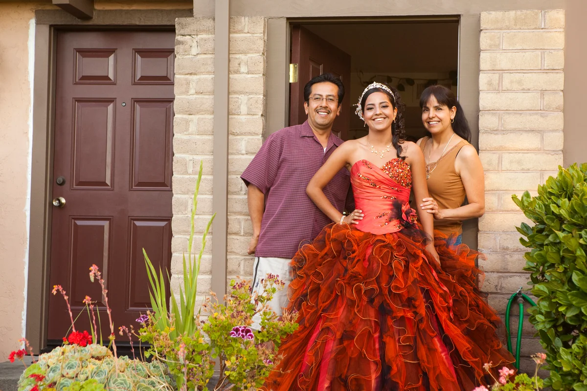 Girl in big red gown posing for picture with parents