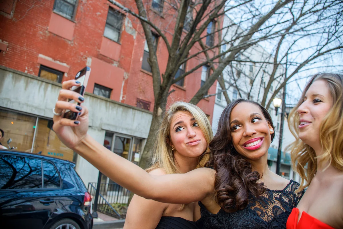 Three young girls taking selfie photos for prom