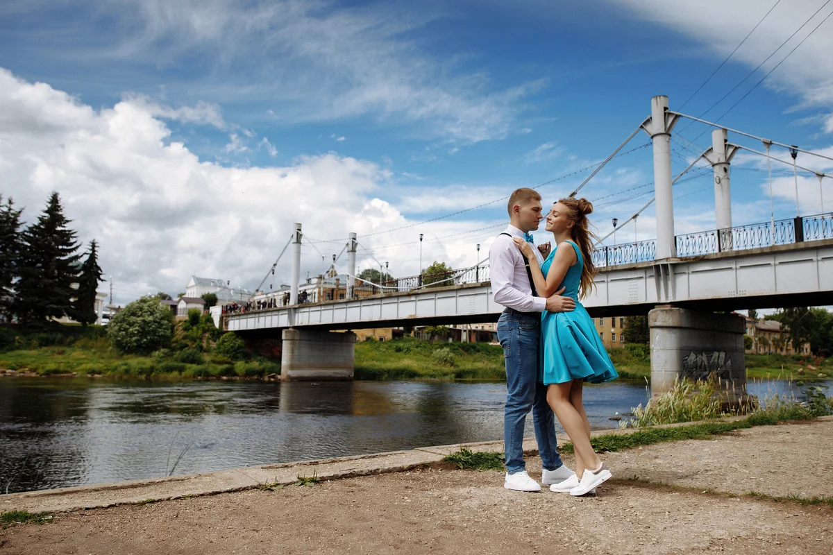 Young couple taking prom photos by bridge