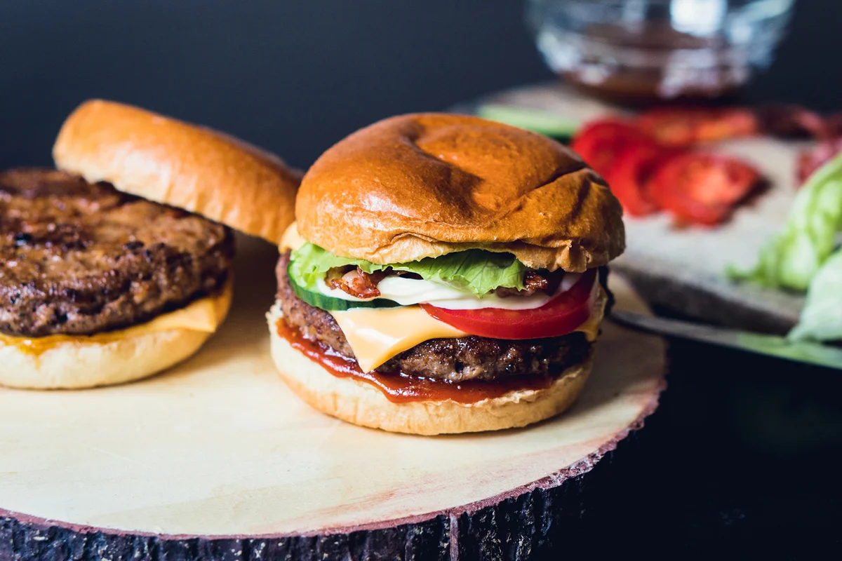 Homemade cheeseburgers with ingredients in the background