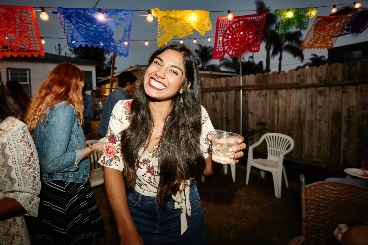 Laughing woman sharing drinks with friends while celebrating Cinco de Mayo