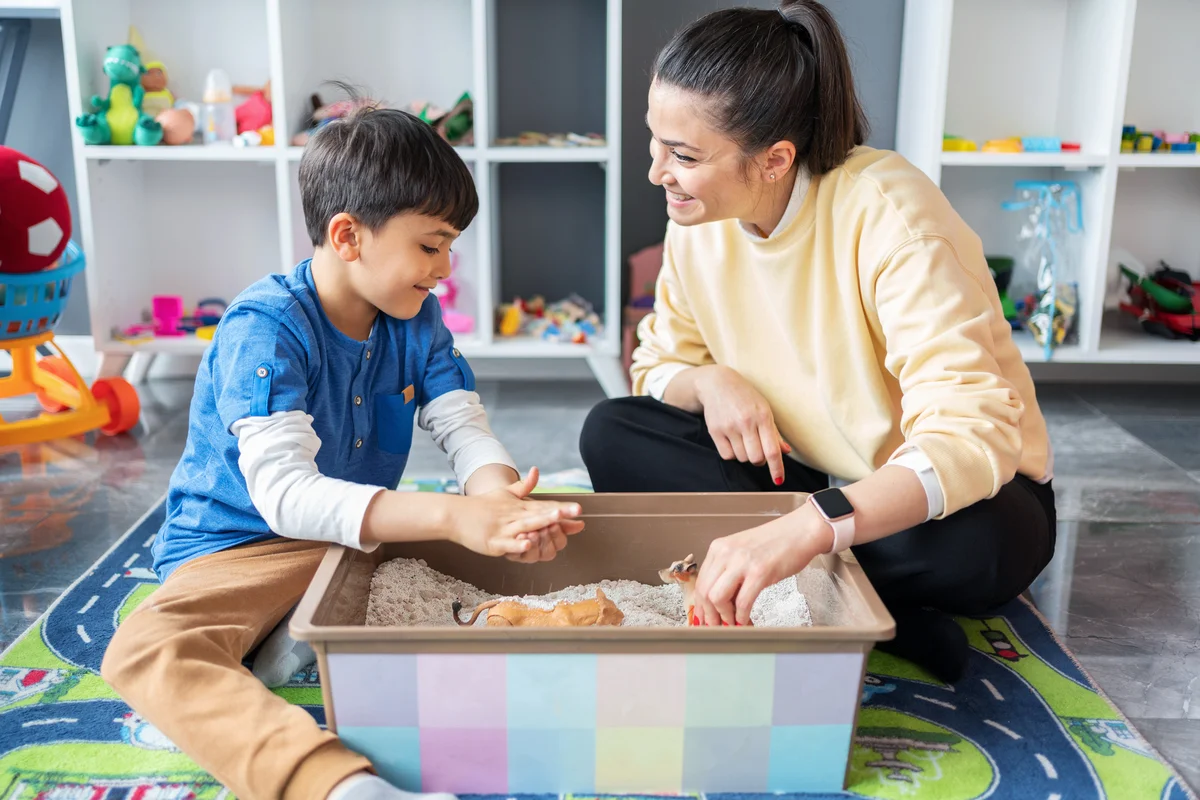 Woman with kid playing with sensory bin