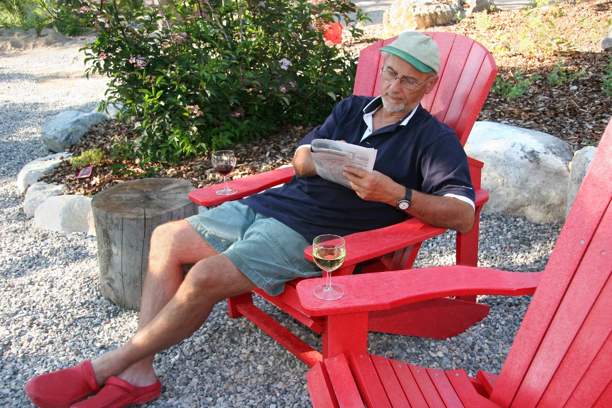Man in garden enjoying some wine and a crossword puzzle