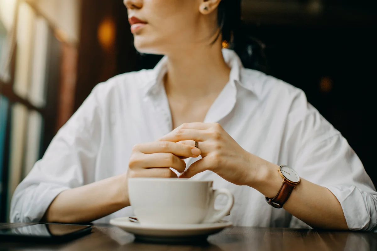 Woman in coffee shop touching her wedding ring
