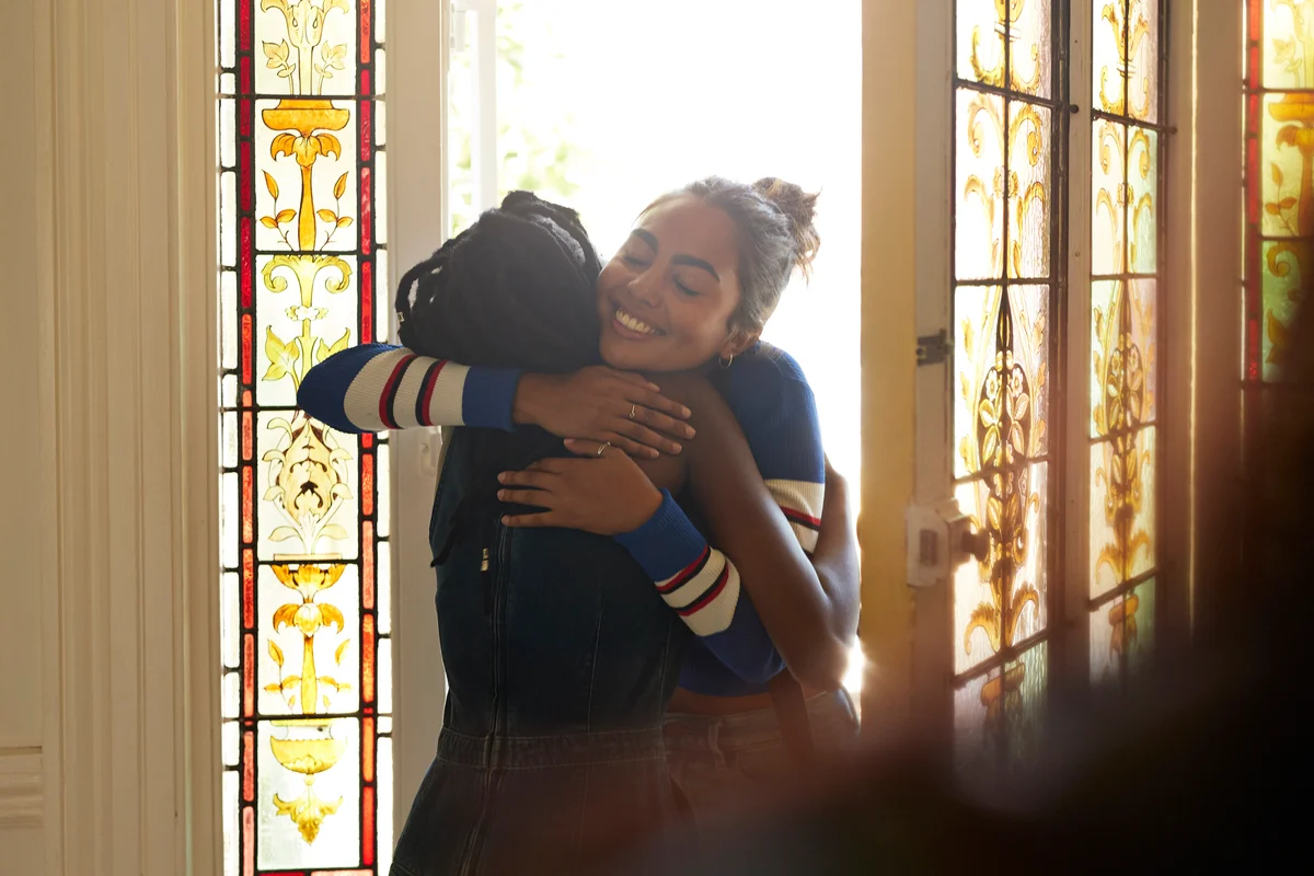 Women reuniting and embracing at doorway