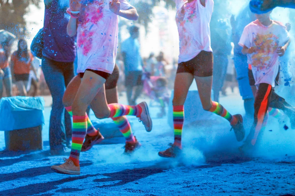 Color run competitors running through blue dye