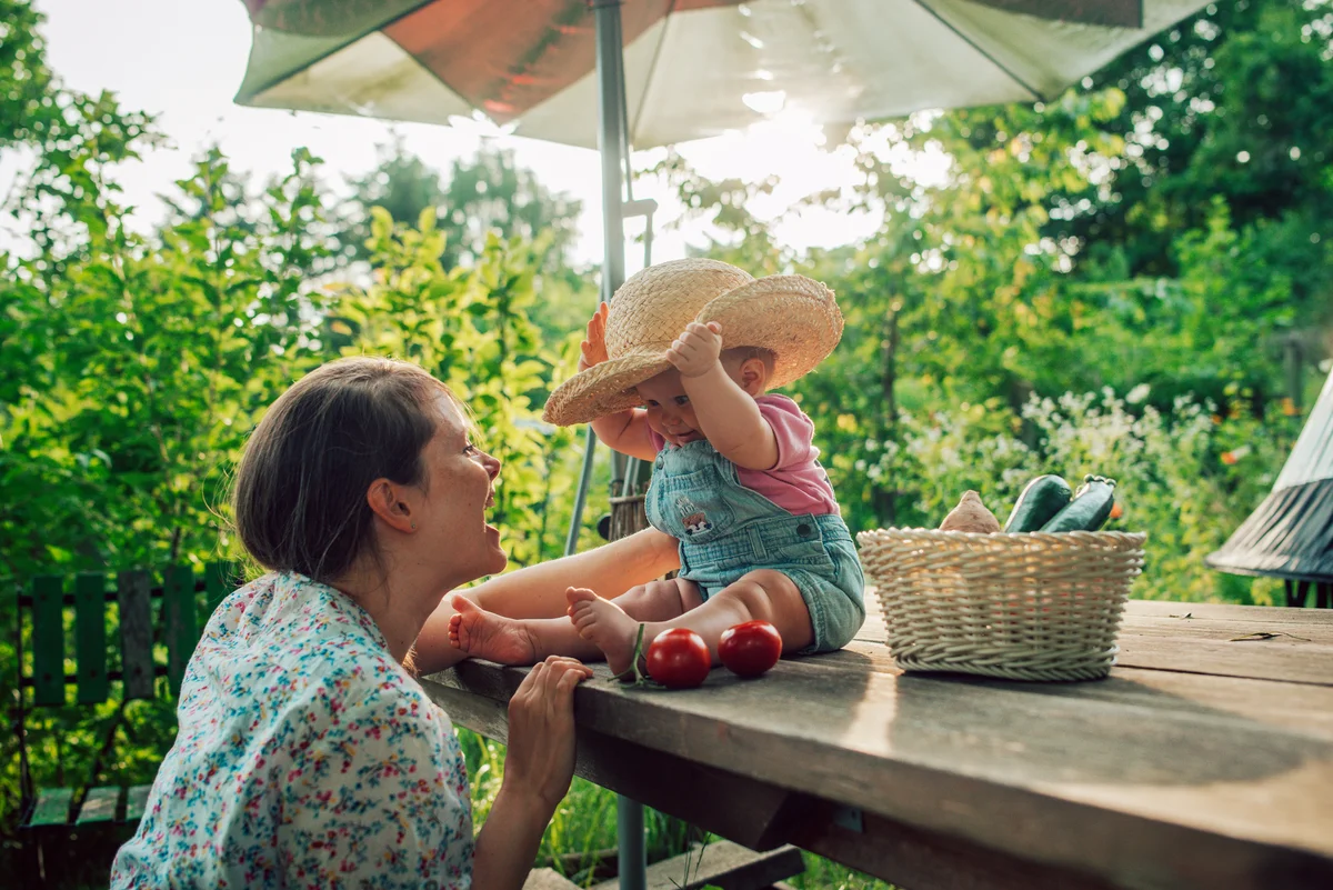 Cheerful mother and daughter having fun while baby tries mother's hat.