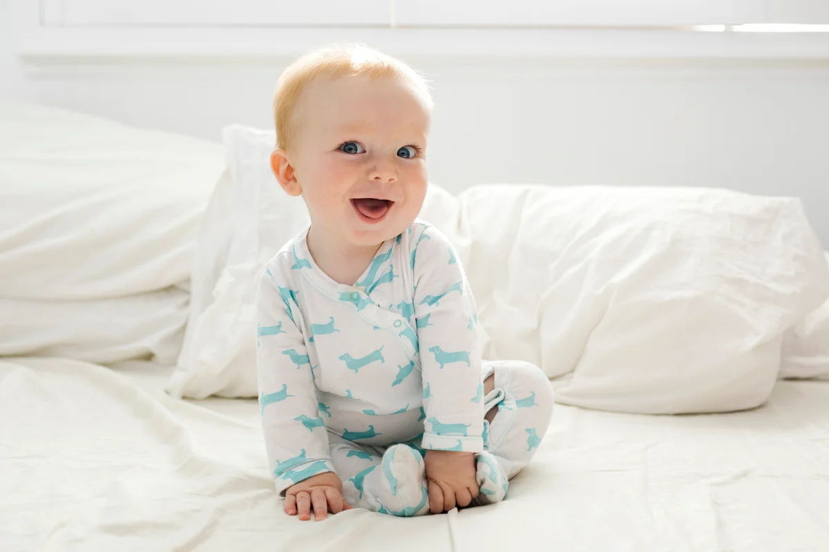 Cute baby boy sitting on bed smiling