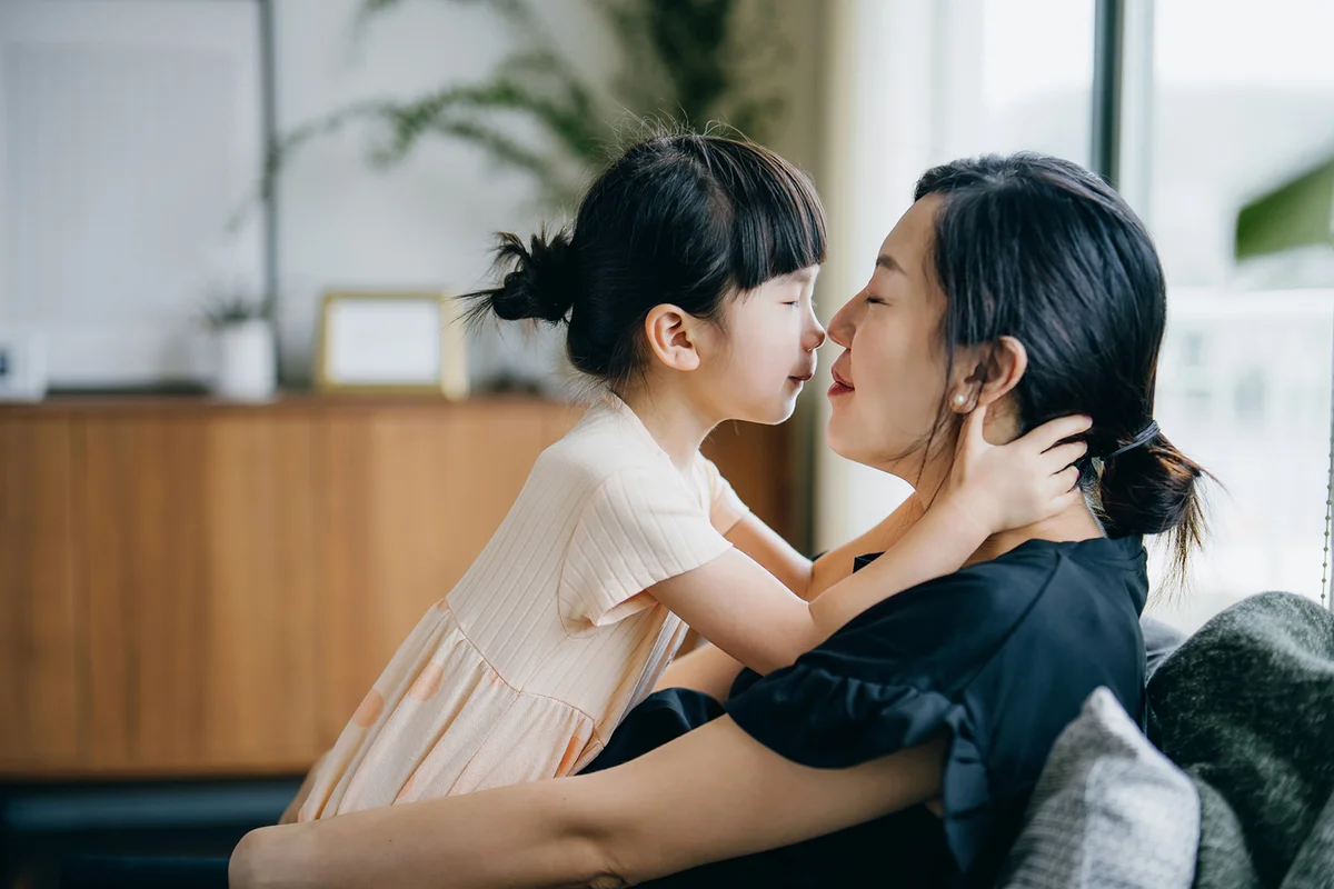 little girl embracing and kissing her mother
