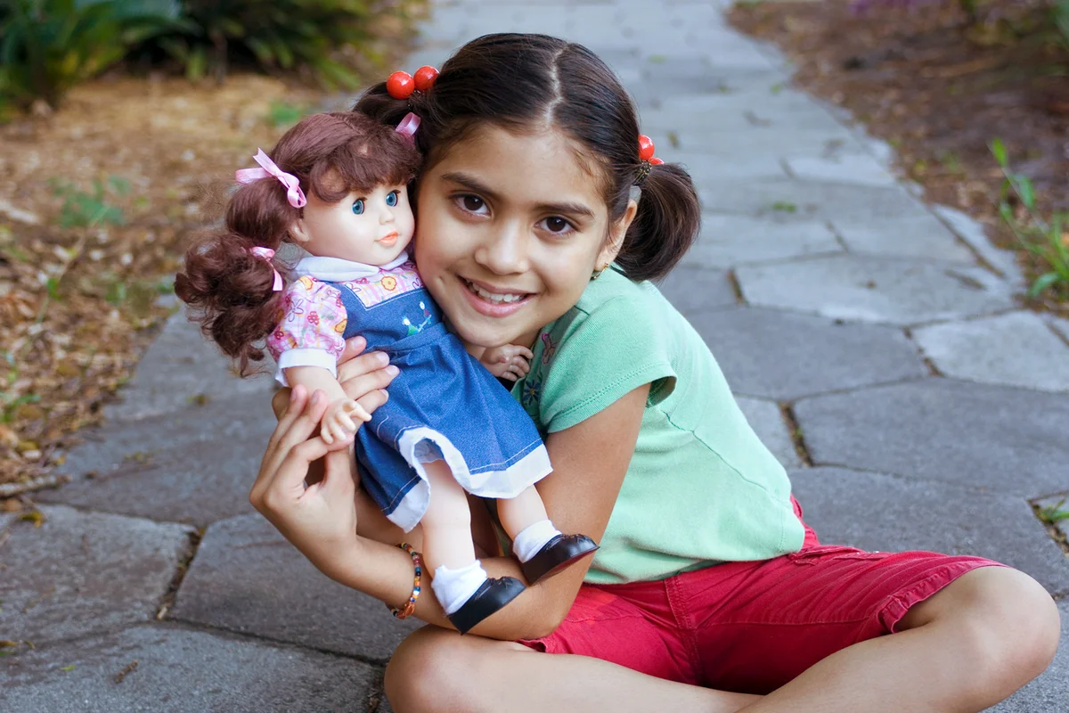 girl poses with her doll.