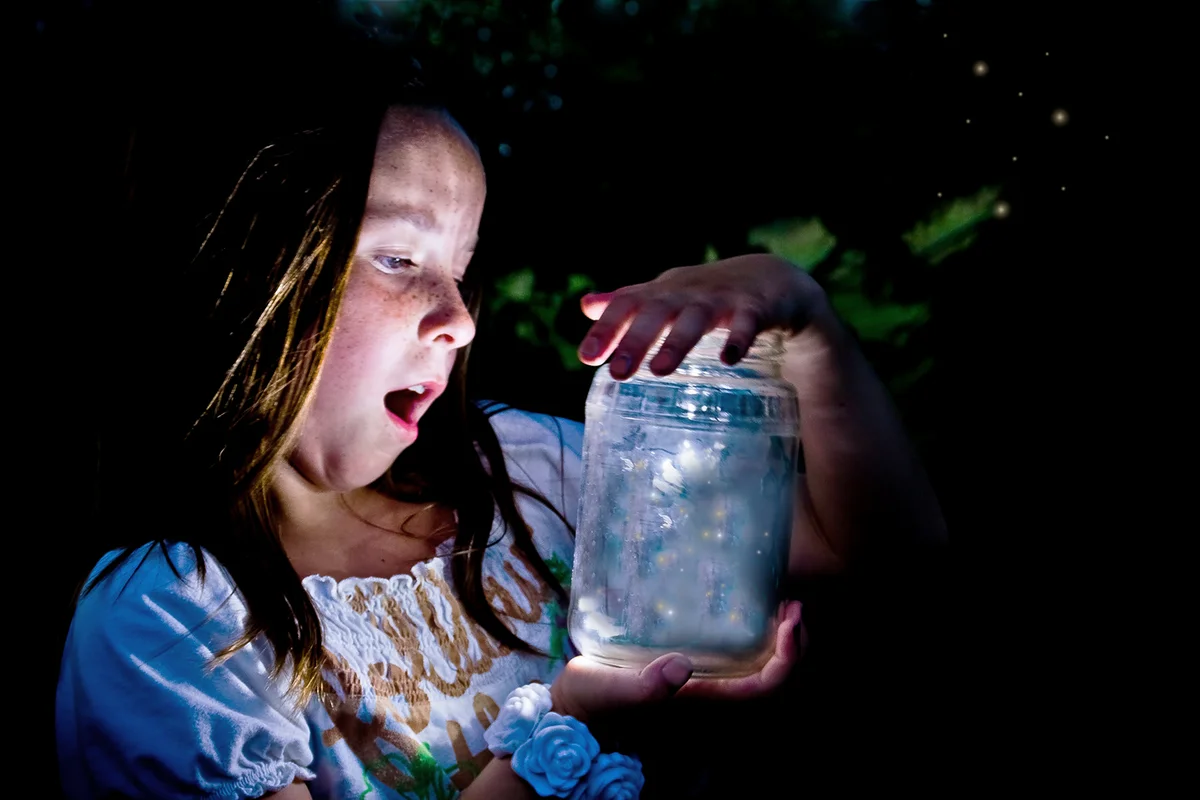 Girl marvels at jar full of fireflies