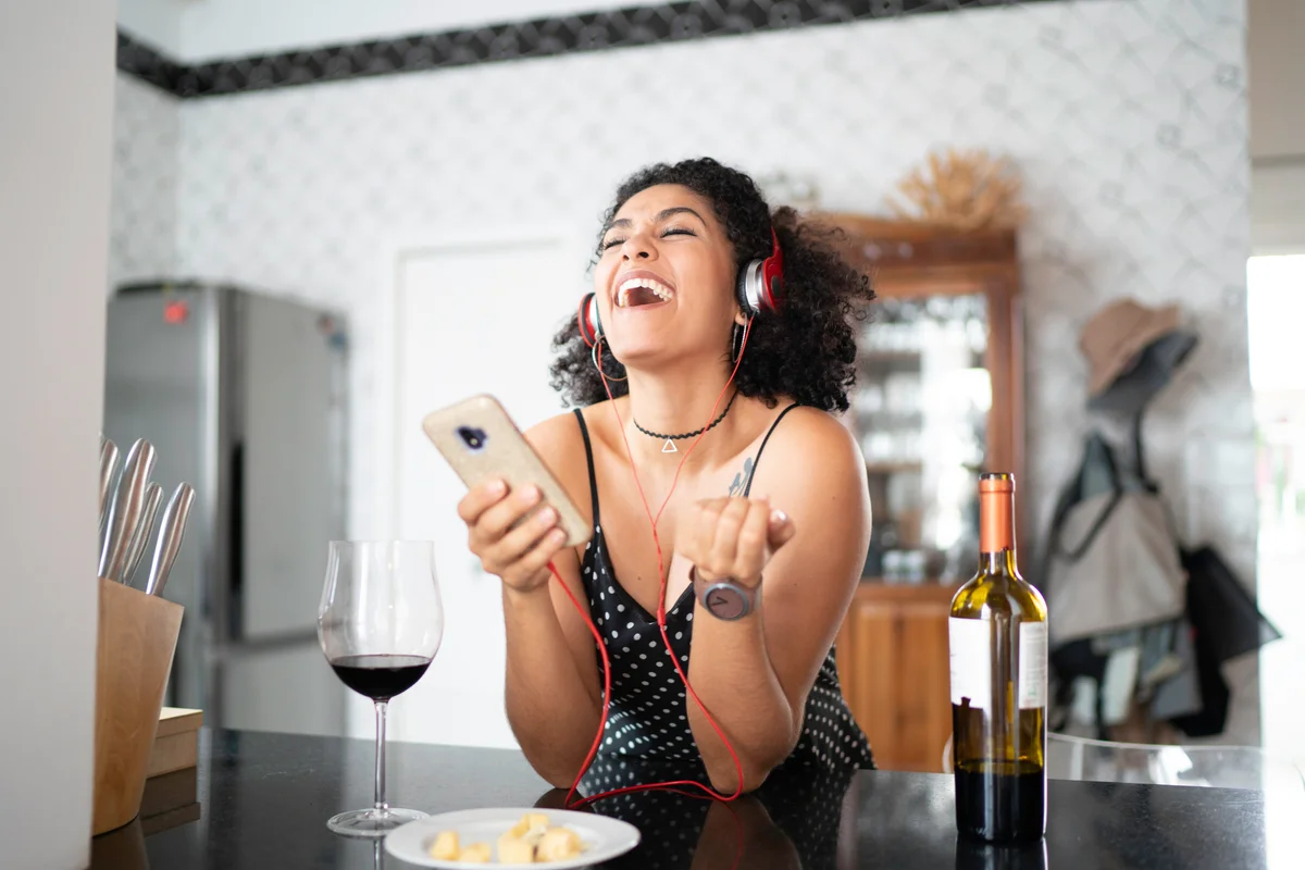 Woman drinking wine while listening her favorite on smart phone