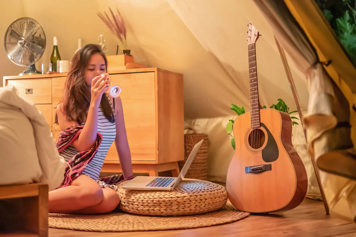 Girl hanging out on bedroom floor on laptop with glass of wine