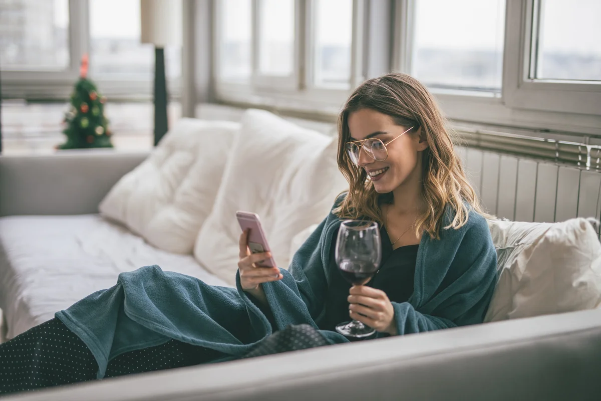 Woman on phone enjoying wine on the couch