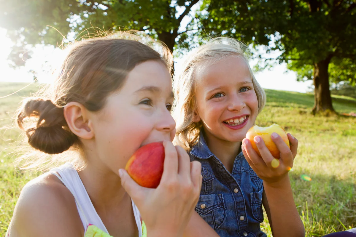 Two girls eating apples