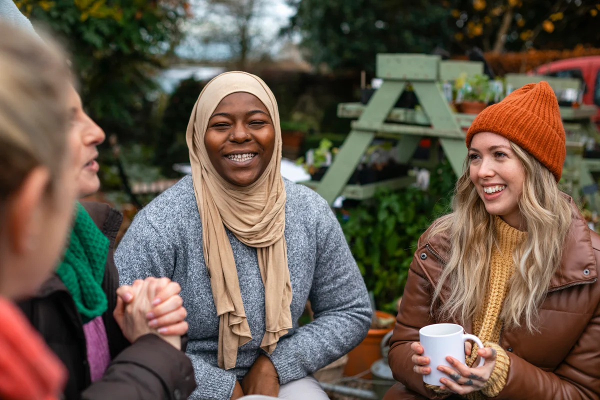 Women drinking hot drinks outside in a circle