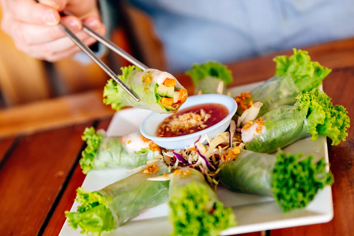 someone eating a spring roll with chopsticks
