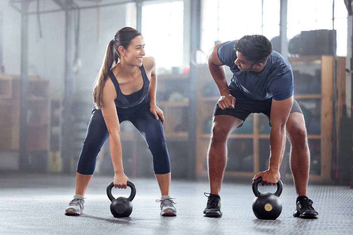 wellness couple doing kettlebell weight exercise