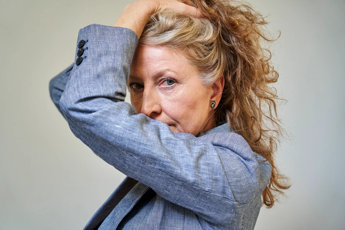 Senior woman holding up long natural wavy blonde and gray hair