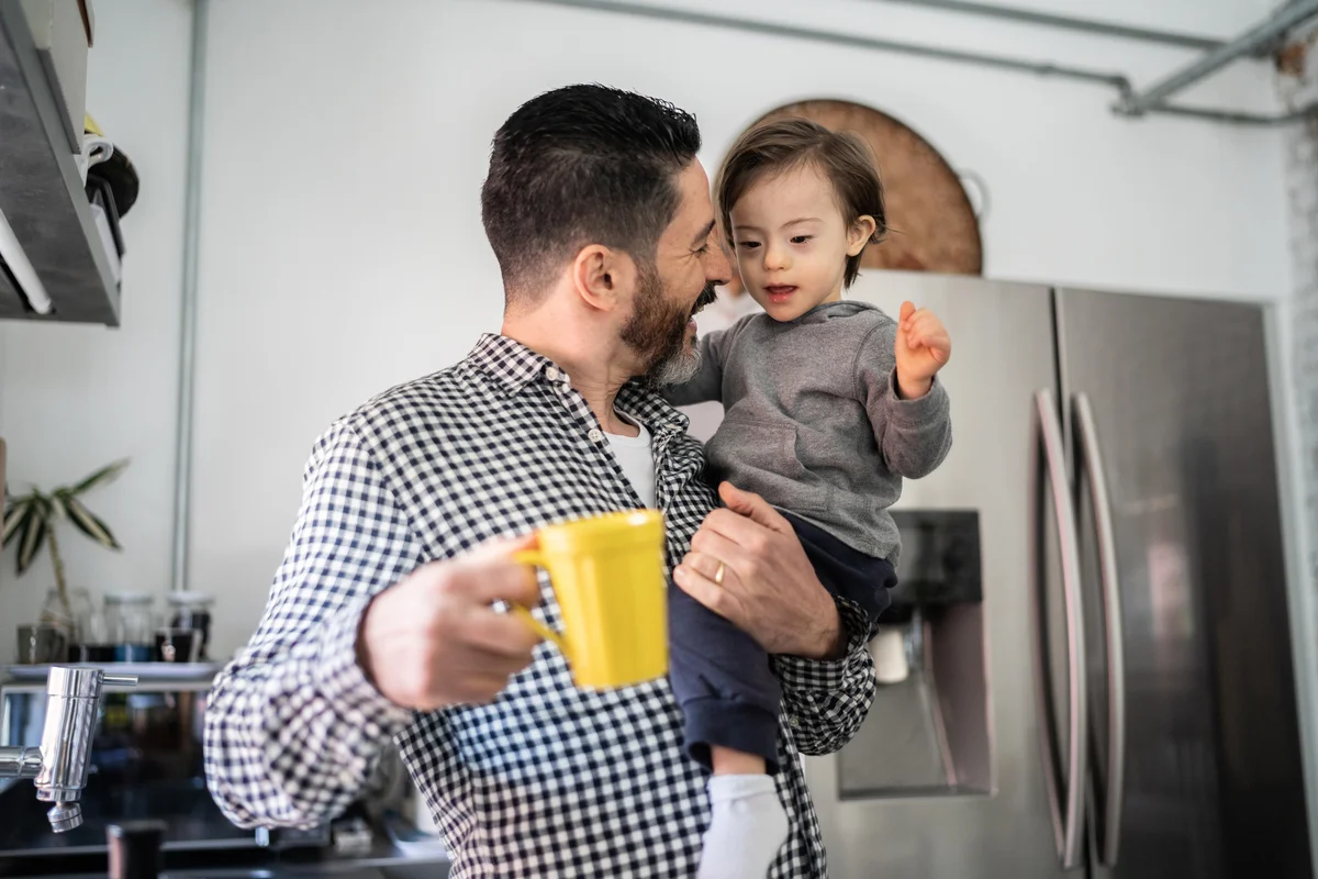 Father holding his toddler son with down syndrome