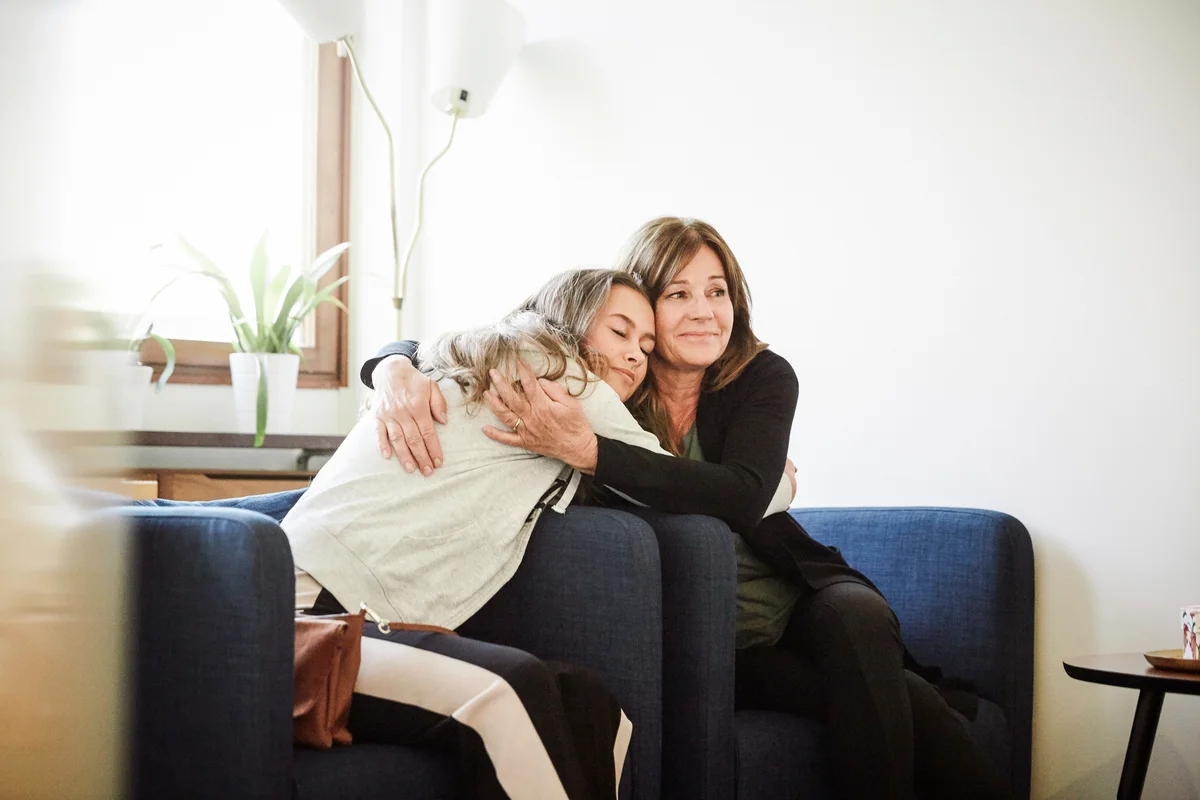 Mom and teen daughter embracing while sitting in chairs