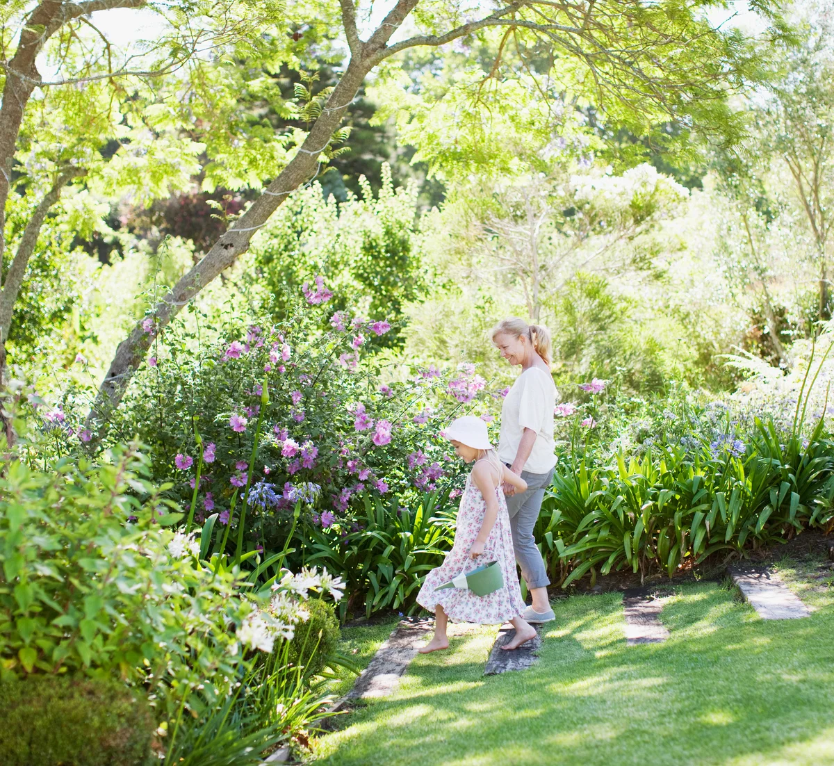 Grandmother and granddaughter walking in cottage garden