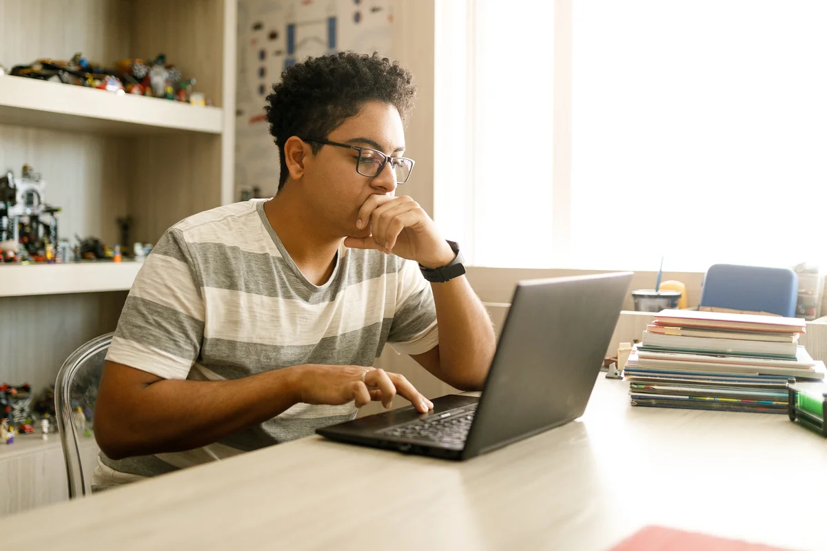 Teen boy studying at desk on laptop